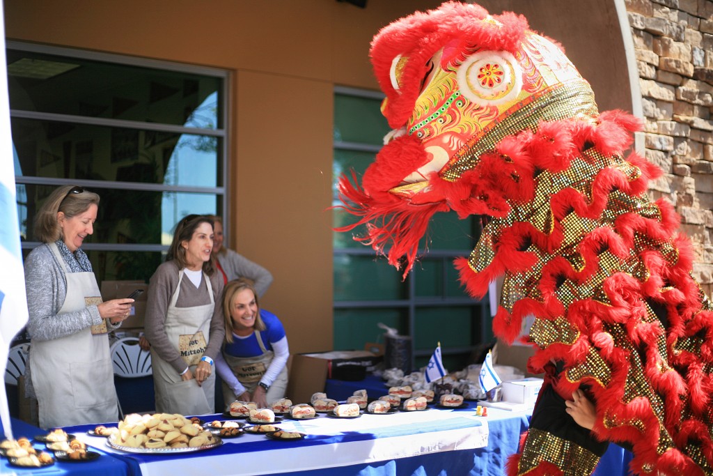 Traditional Chinese lion dancers from the Ane Thanh troupe check out a food booth while the parent volunteers laugh and take photos during the 15th Annual Sage Hill Multicultural Fair on Saturday. — Photo by Sara Hall ©