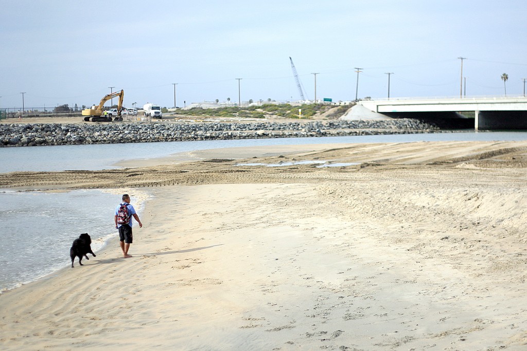 Dogs and people walk along the sand near the Santa Ana River mouth. — Photo by Sara Hall ©