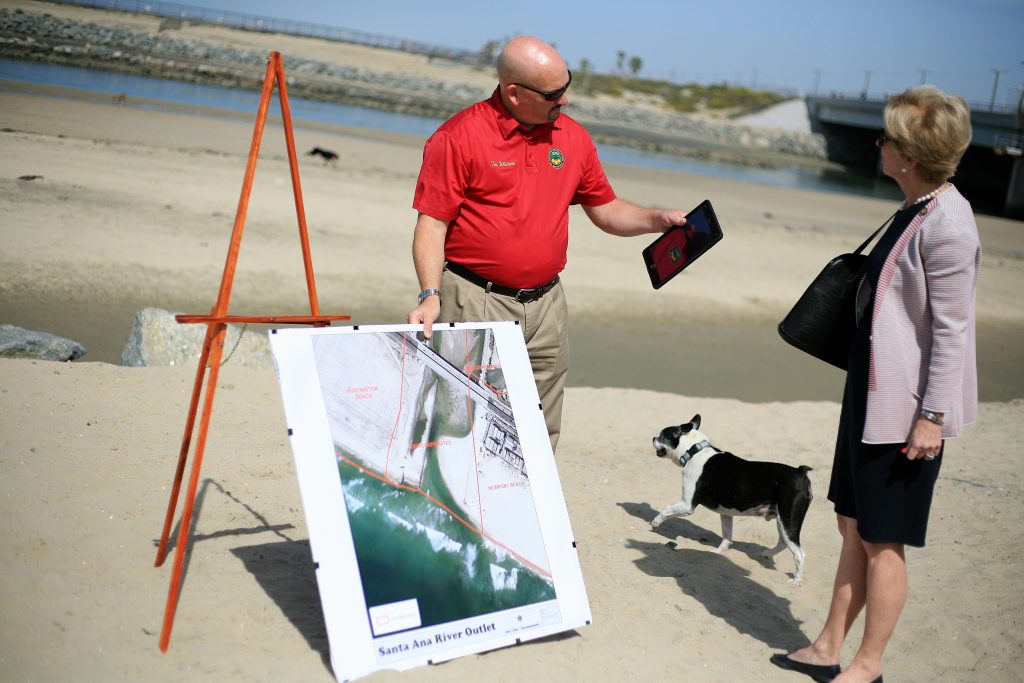 Tim Whitacre, representative for Orange County Board of Supervisors Vice Chair Michelle Steel, and Newport Beach Mayor Diane Dixon discuss the unofficial dog beach at the Santa Ana River mouth as an off leash dog runs by during a press conference on Saturday. — Photo by Sara Hall ©