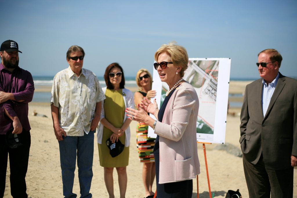 Newport Beach Mayor Diane Dixon (front) speaks to (left to right) council candidate and dog beach proponent Mike Glenn, Newport Beach Councilman Ed Selich, Orange County Board of Supervisors Vice Chair Michelle Steel, OC district 2 staffer (holding sign), NB Councilman Keith Curry, and other officials, dog owners, and residents Saturday about her proposal about making the property at the Santa Ana River mouth an official off leash area for dogs. — Photo by Sara Hall ©