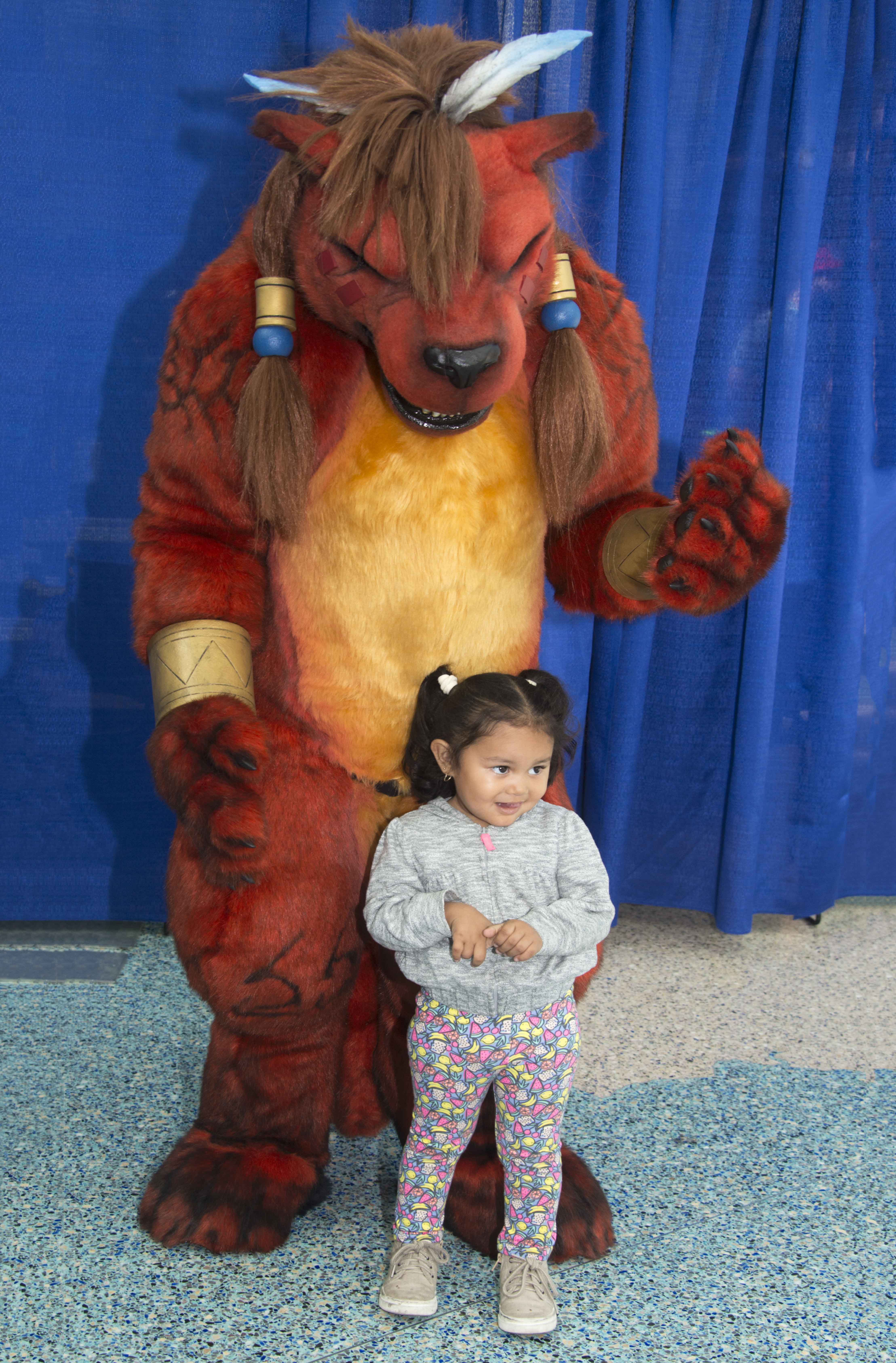 Red XIII, a character from Final Fantasy VII, poses for a photo with a child at WonderCon. — Photo by Lawrence Sherwin ©