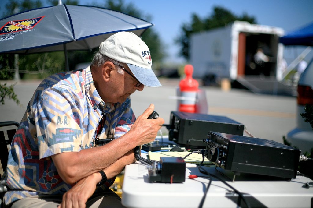 Newport Beach Radio Amateur Civil Emergency Service member Roy Shlemon talks on his ham radio Saturday during the American Radio Relay League Field Day event. The city’s emergency services radio trailer can be seen set up in the background. — Photo by Sara Hall ©