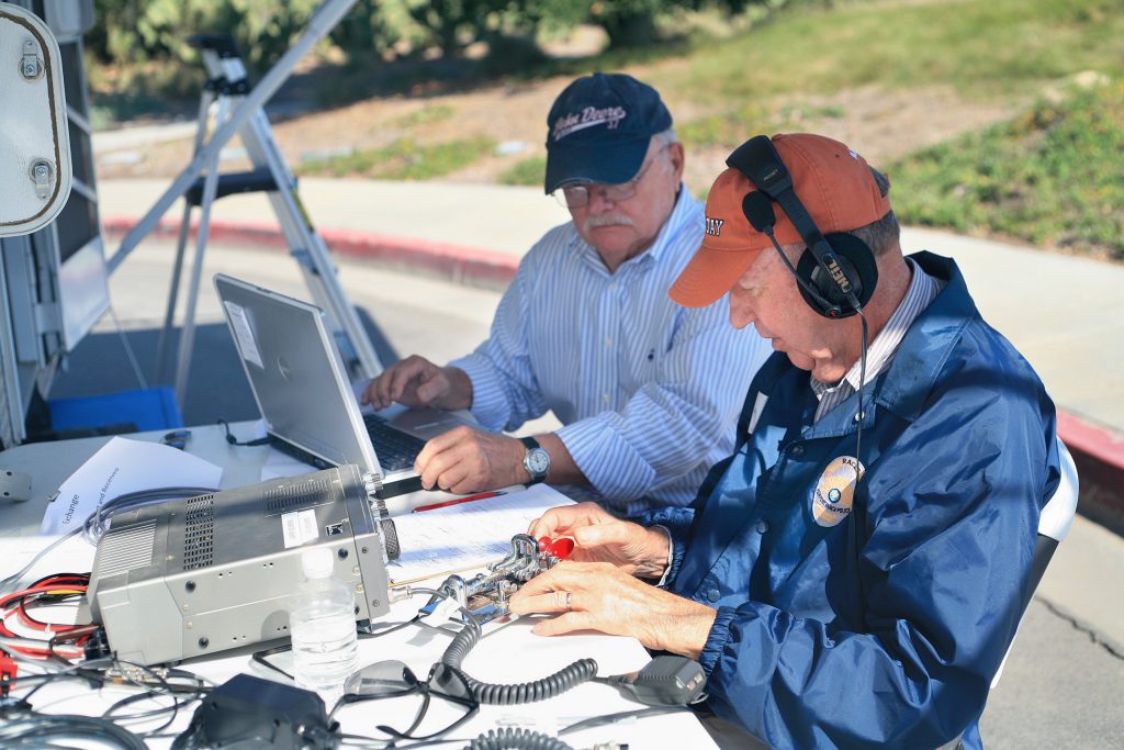 RACES members Bob Carlson (front right) and Jack Buzzard send a Morse code message during ARRL Field Day on Saturday. — Photo by Sara Hall ©