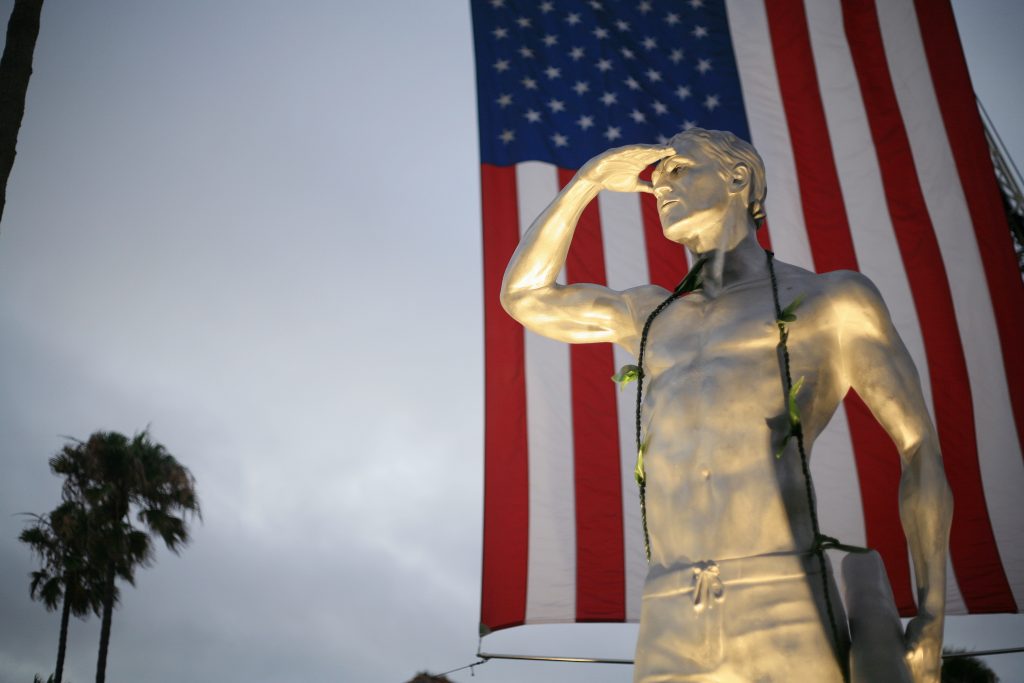 An American flag hangs behind a statue depicting Ben Carlson, the first Newport Beach lifeguard to die in the line of duty, that was unveiled Wednesday night. — Photo by Sara Hall ©