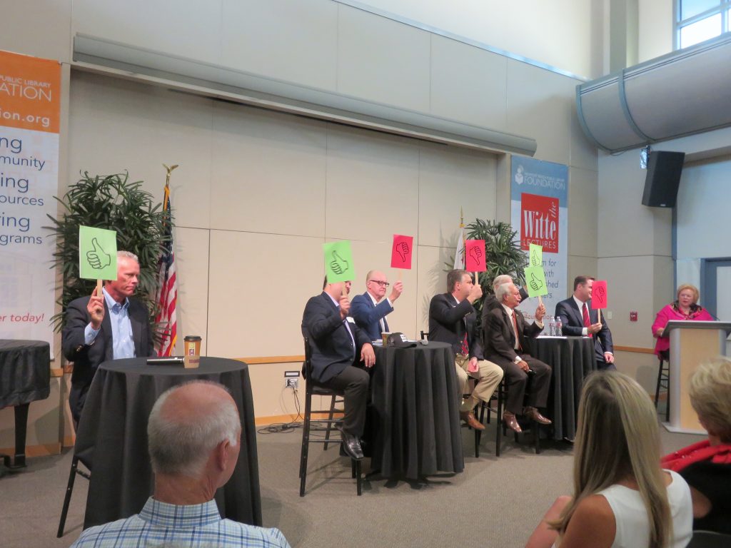 (left to right) Brad Avery in District 2; Mike Glenn, Jeff Herdman, and Lee Lowrey for District 5; and Fred Ameri, Phil Greer (hidden slightly in background), and Will O’Neill for District 7, use"thumbs up" or "thumbs down" paddles to answer a question asked by moderator Lucy Dunn at the NB Chamber candidate forum on Tuesday. — Photo by Sara Hall ©