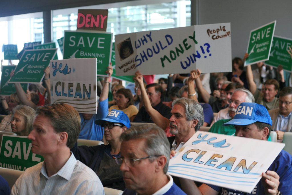 Banning Ranch project protesters and supporters wave signs during the California Coastal Commission meeting Wednesday. — Photo by Sara Hall ©