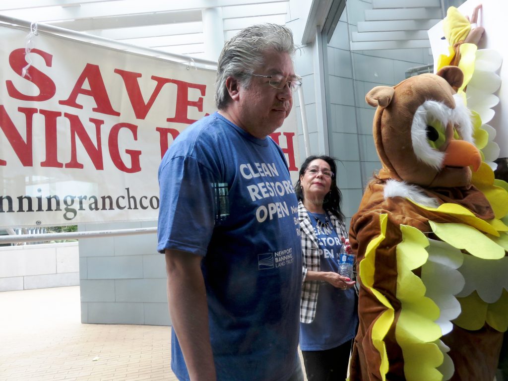 A NBR supporter and an opponent dressed as an owl watch the Coastal Commission meeting from outside the window. — Photo by Sara Hall ©