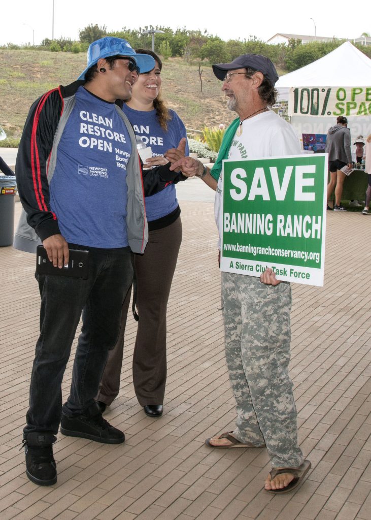 Banning Ranch supporters Guillermo Durado and Vanessa Roque talk with opponent Johnny Hawk outside the CCC meeting on Wednesday. — Photo by Charles Weinberg ©