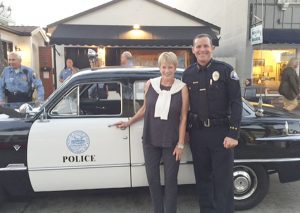 Balboa Island Museum and Historical Society President Shirley Pepys and Newport Beach Police Chief Jon Lewis pose in front of a classic Ford police cruiser.