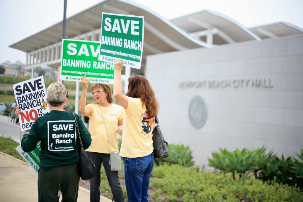 Opponents of the Banning Ranch project wave signs outside the Newport Beach Civic Center on Thursday morning. The California Coastal Commission met in NB council chambers and was scheduled to vote on the controversial project on May 12, but it was postponed. — Photo by Sara Hall ©