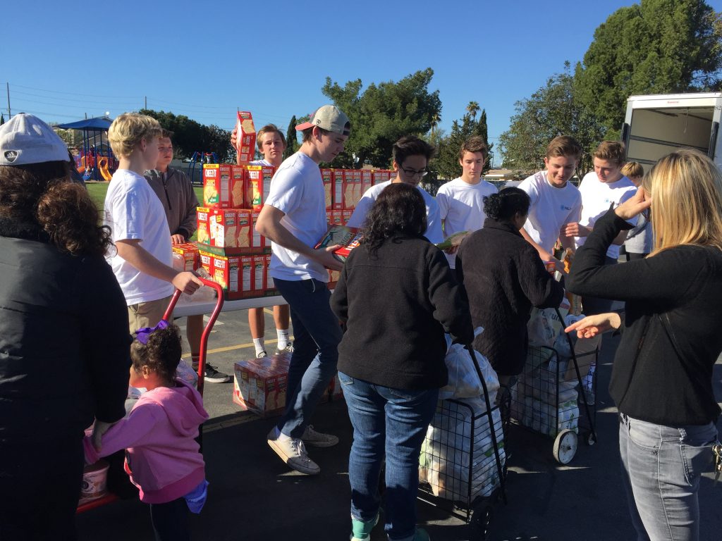 Members of the Newport-Mesa chapter of the National League of Young Men hand out food to people in need at an event on Saturday. — Photo courtesy of NLYM ©