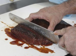 Sterling Ball, founder of Big Poppa Smokers, slices brisket (photo by Chris Trela)