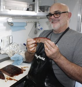 Sterling Ball, founder of Big Poppa Smokers, holds a prize slice of brisket (photo by Chris Trela)