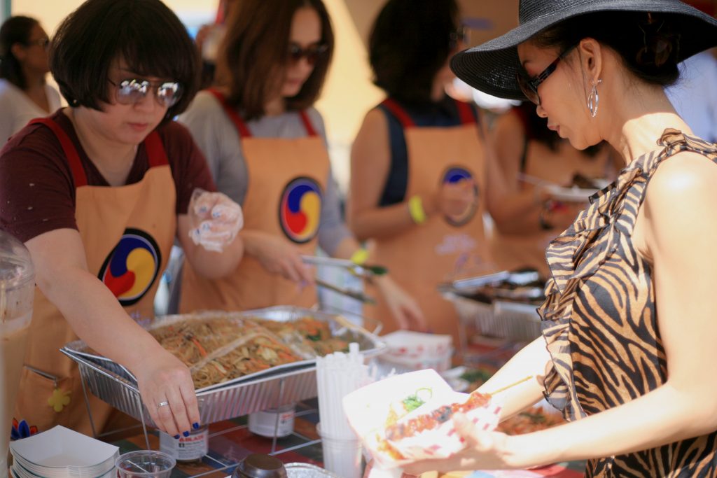 Sage parent Bee Walbridge picks out some food from the Korean food booth on Saturday. — Photo by Sara Hall ©