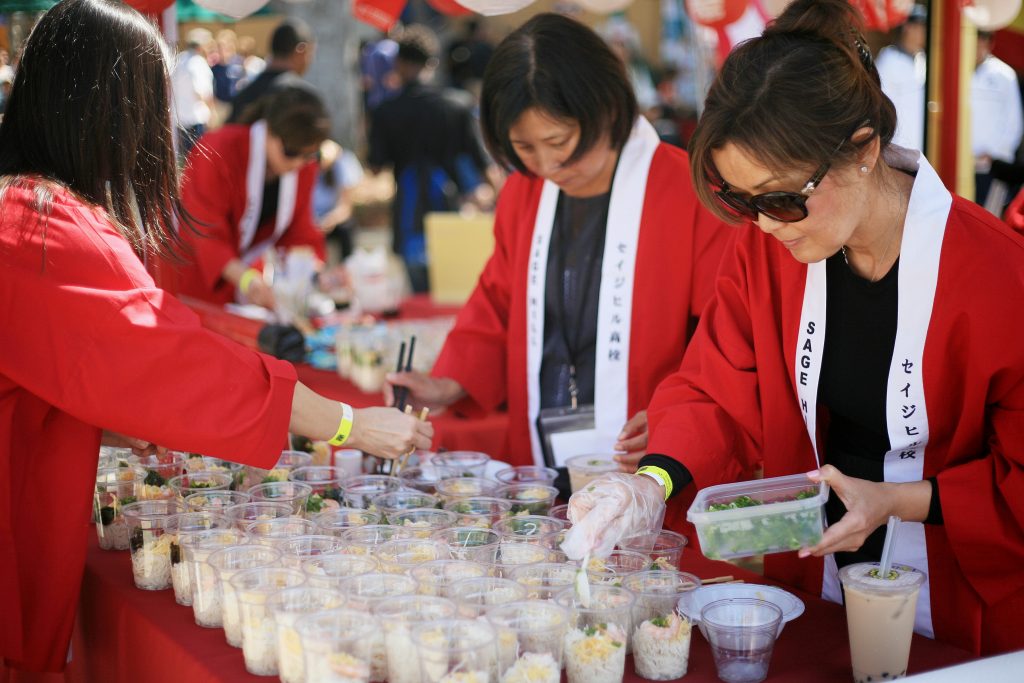 Sage parents (left to right) Junko Hara, Emi Nishinaka and Reiko Stauss fill cups with chilled somen noodles for the Japan food booth. — Photo by Sara Hall ©