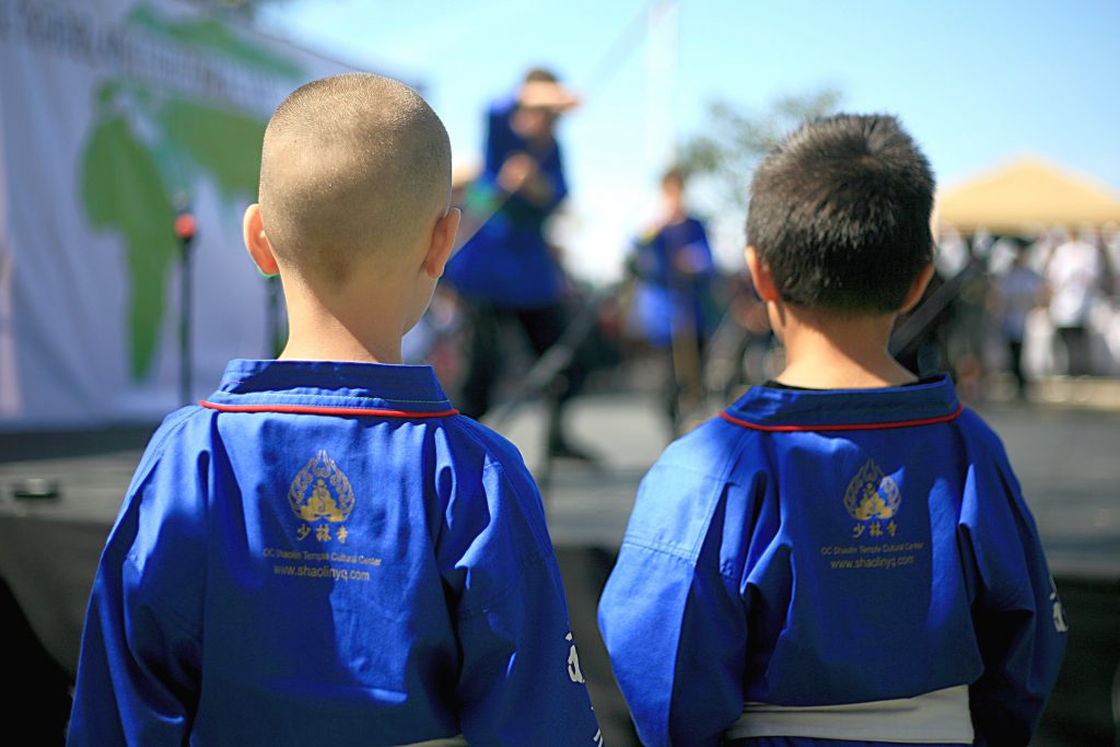 Two of the younger members of Kung Fu Master Shi Yanqing from the Orange County Shaolin Temple Cultural Center in Costa Mesa watch as their fellow Kung Fu trainees perform on stage. — Photo by Sara Hall ©