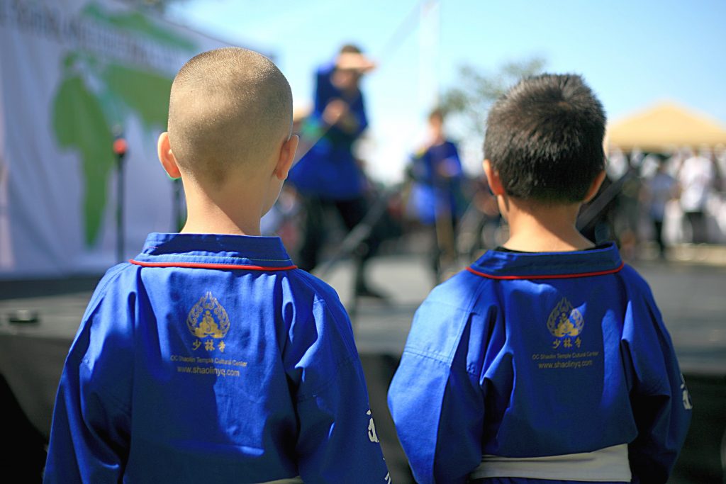 Two of the younger members of Kung Fu Master Shi Yanqing from the Orange County Shaolin Temple Cultural Center in Costa Mesa watch as their fellow Kung Fu trainees perform on stage.  — Photo by Sara Hall ©