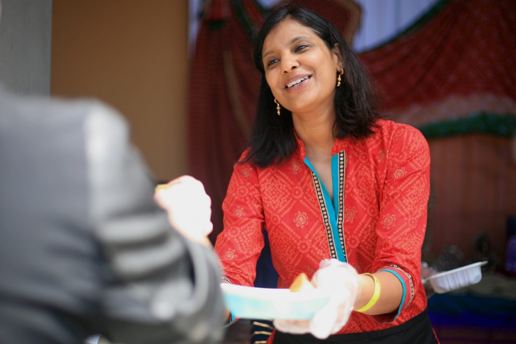 Shilpa Kamdar, mom of a Sage Hill student, smiles and hands a guest food from the India booth on Saturday. — Photo by Sara Hall ©