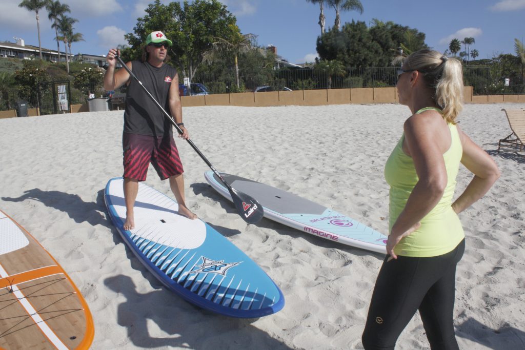 NB Indy columnist Shelly Zavala gets a demonstration on how to use a stand up paddleboard before hitting the water when she rented a SUP during a previous summer. — Photo by Christopher Trela ©