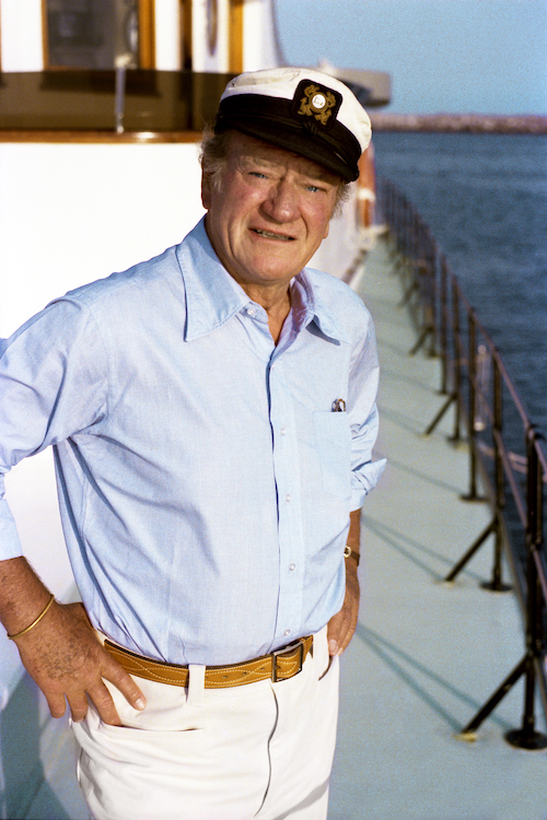 John Wayne aboard his boat, Wild Goose, which was - and still is- docked in Newport Harbor. — Photo courtesy John Wayne Enterprises ©