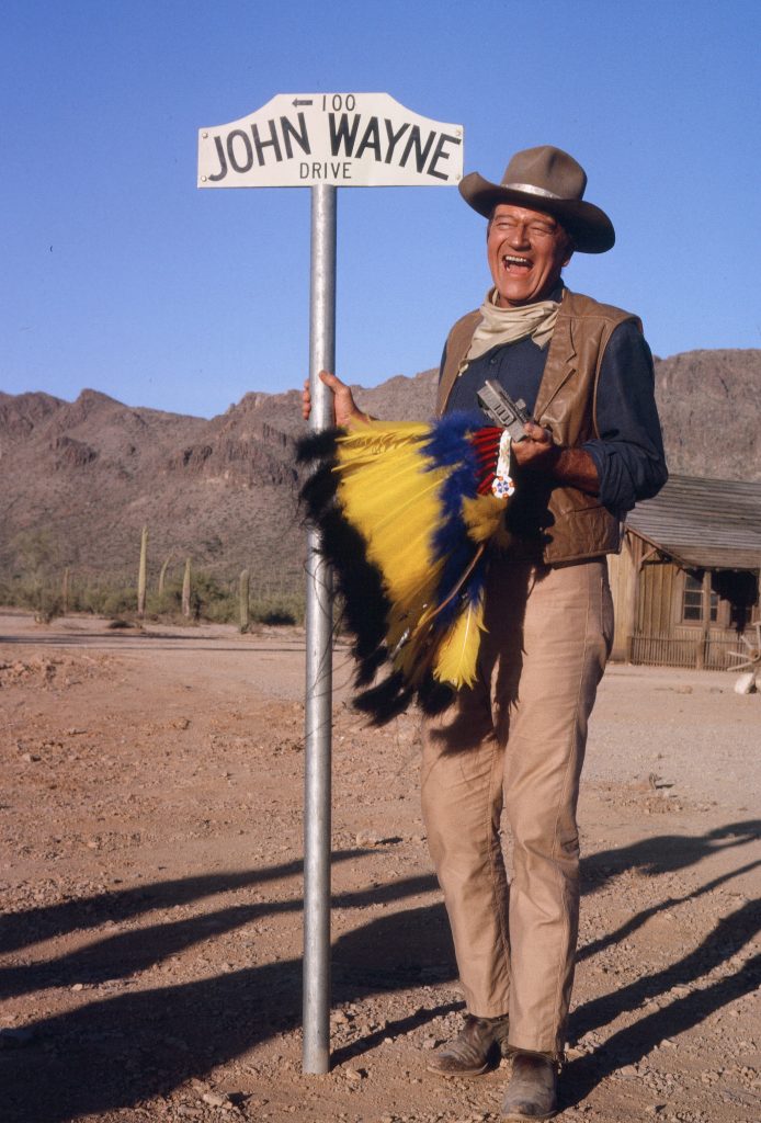 John Wayne with the street sign named after him on the “El Dorado” movie set in 1966.  — Photo courtesy John Wayne Enterprises ©